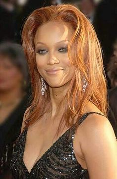 a woman with long red hair wearing a black dress and diamond earrings on her head