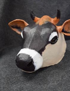 a fake cow head sitting on top of a gray couch next to a black and white pillow