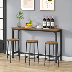 three bottles of wine sit on a table with two stools in front of it