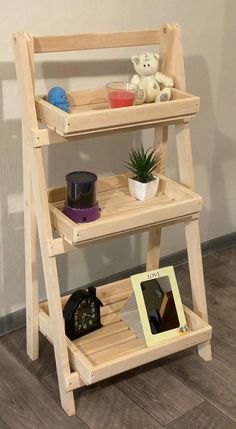 a three tiered wooden shelf with pictures and toys on the bottom shelf, next to a small potted plant