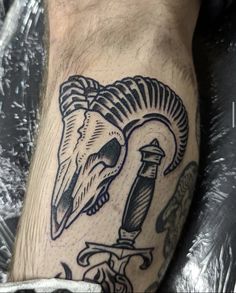 a man's leg with a goat skull and dagger tattoo on his left calf