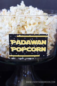 a bowl filled with popcorn sitting on top of a table next to a sign that says padawan popcorn