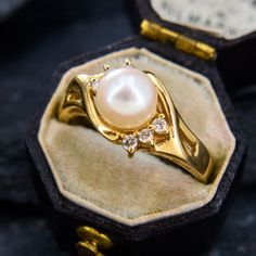 a close up of a ring in a box with a pearl on the front and side