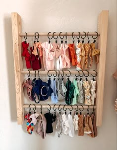 a wooden rack with several pairs of baby shoes hanging from it's hooks on the wall