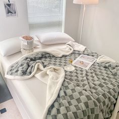 a bed with a blanket and pillows on it next to a lamp in a bedroom