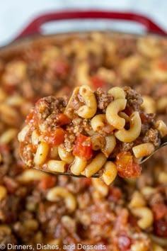 a ladle full of chili macaroni and cheese is being held by a spoon