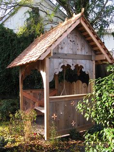 a wooden gazebo in the middle of a garden