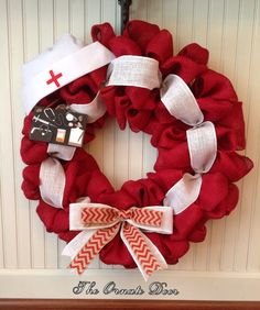 a red wreath with white ribbons and a cross on it is hung on the front door