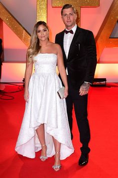 a man and woman in formal wear standing on the red carpet at an awards event