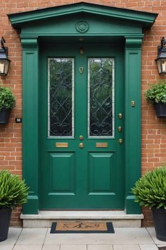 a green front door with two potted plants