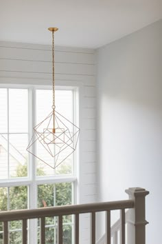 a chandelier hanging from the ceiling in a room with white walls and windows