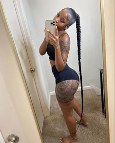 a woman taking a selfie in the mirror with her hair pulled back and tattoos on