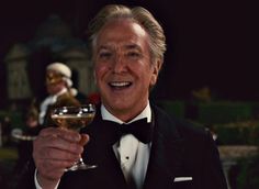 an older man in a tuxedo holding a glass of wine and smiling at the camera