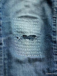 an insect is seen through the holes in a pair of blue denim jeans that have been stitched together