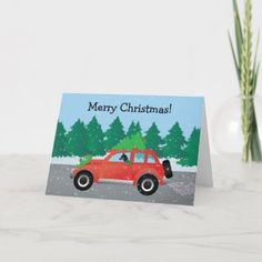 a christmas card with a red car driving down the road in front of some yellow flowers