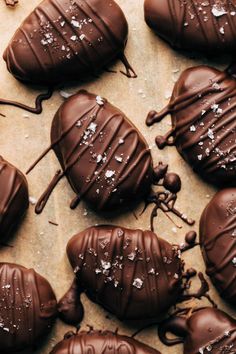 chocolate covered pastries with white sprinkles are arranged on a piece of parchment paper