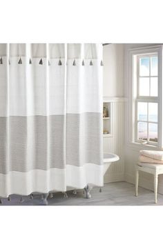 a white and gray shower curtain in a bathroom next to a tub with a window