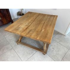 a wooden table sitting on top of a tile floor next to a cabinet and door