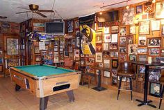 a pool table in a room with many pictures on the wall