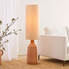 a table lamp sitting on top of a rug next to a white couch and chair