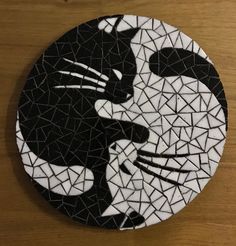 a black and white mosaic tile with a cat kissing on it's face in front of a wooden table