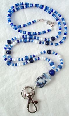 Blue & White Beaded Lanyard This Blue & White Beaded Lanyard can be used as a badge holder, an I.D. holder, keychain necklace, watch holder - it's a multi-use accessory for home or office! 34" in length, long enough to put on or remove overhead. It also has an easy-to-use metal lobster clasp for your convenience. It's made with blue and white glass beads and strung on strong C-Lon beading cord. Snap-on badge holder, clip, and keyring are included to keep your badges or keys ready when you need t Adjustable Beaded Blue Lanyards, Adjustable Blue Beaded Lanyards, Blue Beaded Jewelry For Everyday Use, Everyday Blue Beaded Jewelry, Blue Round Beads Jewelry For Everyday, Handmade Blue Lanyards For Gifts, Handmade Blue Lanyard As Gift, Handmade Blue Lanyards As Gifts, Blue Lanyard With Key Leash As Gift