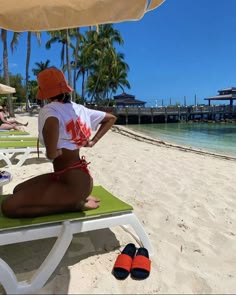 a woman sitting on top of a beach under an umbrella