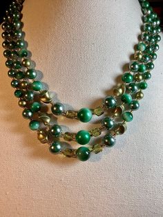 Attractive vintage lucite and glass Japanese 3 strand bib necklace. Large green lucite bead from 13mm down to 7mm round with similar size twisted beads. The addition of 8mm transparent green faceted glass beads and glass seed bead spacers really clinches the elegant look. The complete shortest length with 3 inch adjustable extension is 19 inches. Stamped Japan on the silver tone clasp. Good condition with little wear and a hook clasp. (B484) Vintage Green Double Strand Necklaces, Vintage Green Double Strand Necklace, Multi-strand Green Large Beads, Green Double Strand Beaded Necklace, Green Double Strand Necklace With Faceted Beads, Vintage Green Faceted Beads, Vintage Green Beads For Jewelry Making, Vintage Green Beaded Necklaces With Round Beads, Vintage Green Beaded Necklace With Round Beads