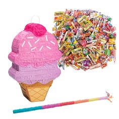 an ice cream cone with candy in it next to a large pile of candies