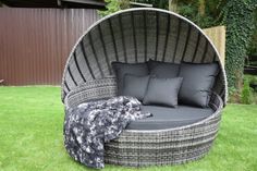 an outdoor lounge chair with pillows on the grass