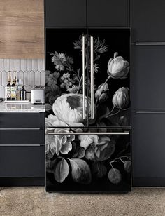 a black and white kitchen with flowers painted on the refrigerator