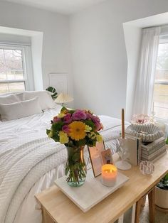 a bed room with a neatly made bed and flowers on the table next to it