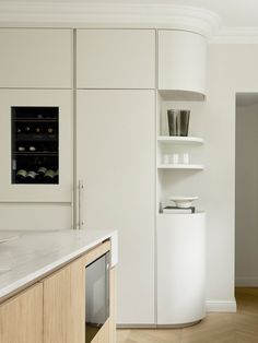 a kitchen with white cupboards and marble counter tops, along with wooden flooring