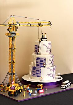 a cake with legos on it sitting next to a construction crane