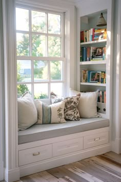 a window seat with bookshelves and pillows on it