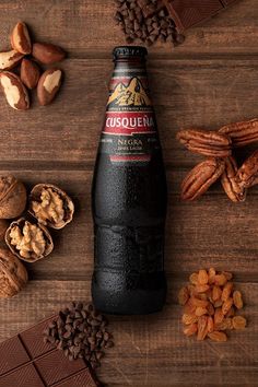 a bottle of beer next to nuts and chocolate on a wooden table with other ingredients