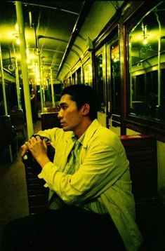 a man sitting on a subway train with his hands in his pockets and looking off into the distance