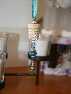 a candle holder with some beads hanging from it's side on a wooden table