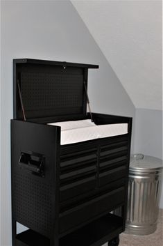 an empty toolbox sitting in the corner of a room next to a trash can