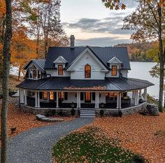 a large white house sitting on top of a lush green field next to a lake