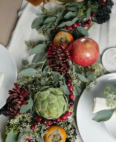 an arrangement of fruits and vegetables is arranged on a table with plates, napkins and utensils