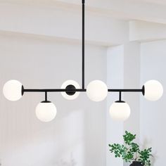 a black chandelier with five white balls hanging from it