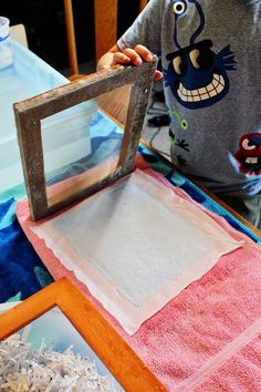 a young boy is working on an art project with paper and wood shavings