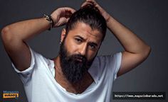 a man with a beard and white shirt is holding his hands on his head while looking at the camera