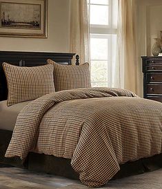 a bed in a bedroom with brown and white checkered comforter set on it