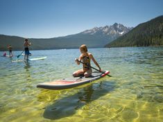 a woman sitting on top of a surfboard in the water next to other people