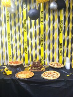 some pizzas are sitting on a table in front of yellow and black streamers