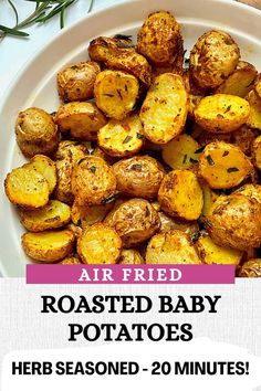 a white plate topped with cooked potatoes next to a wooden spoon and rosemary sprigs