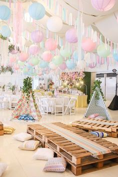 a room filled with lots of colorful paper lanterns hanging from the ceiling and pillows on the floor