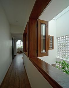 an empty hallway with wooden doors and windows on both sides, leading to another room